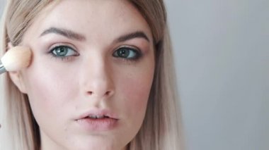 Kalıcı makyaj. Genç güzel kız makyaj fırça ile yanaklarda yapma.