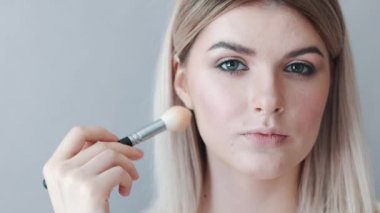 Kalıcı makyaj. Genç güzel kız makyaj fırça ile yanaklarda yapma.