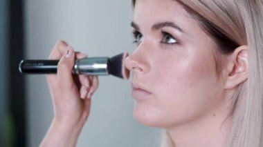 Kalıcı makyaj. Genç güzel kız makyaj fırça ile yanaklarda yapma