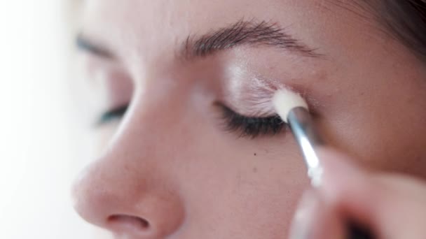 Visagist målar ögonen med ögonskugga en ung flicka — Stockvideo