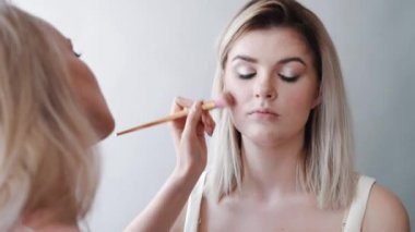 Kalıcı makyaj. Genç güzel kız makyaj fırça ile yanaklarda yapma.