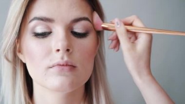 Kalıcı makyaj. Genç güzel kız makyaj fırça ile yanaklarda yapma.