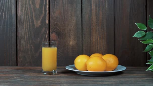 Suco de laranja recentemente apertado em um copo. Despeje, esprema o suco de laranja. Em um fundo de madeira . — Vídeo de Stock