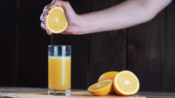 Jus d'orange fraîchement pressé dans un verre. Verser, presser le jus d'orange. Sur un fond en bois . — Video