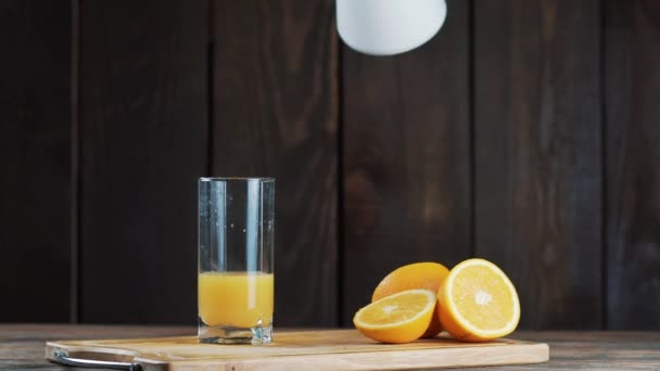 Vers geperst sinaasappelsap in een glas. Pour, oranje sap persen. Op een houten achtergrond. — Stockvideo