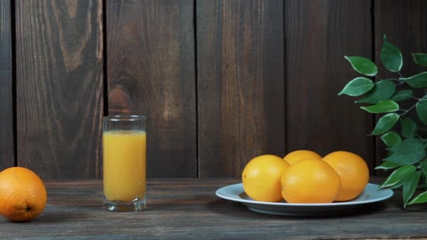 Frissen facsart narancslé egy pohár. Pour, nyomja össze a narancslé. A fából készült háttér. — Stock videók