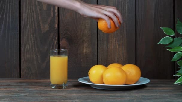 Frissen facsart narancslé egy pohár. Pour, nyomja össze a narancslé. A fából készült háttér. — Stock videók