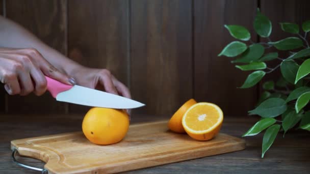 Mujeres manos corte naranja fresca en la cocina — Vídeo de stock