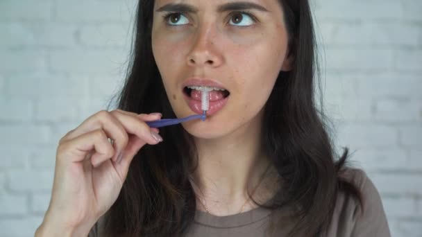 Higiene oral para aparatos ortopédicos. La joven con aparatos dentales se limpia los dientes. Chica adolescente limpiando y cepillando dientes con frenos de cerámica transparente usando herramientas especiales de cepillado . — Vídeos de Stock