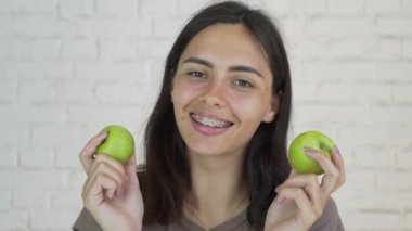 Yeşil elma ve gülümseme yeme dişlerini üzerinde parantez kadın var. Beyaz. Portre
