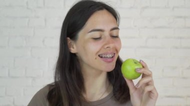 Yeşil elma ve gülümseme yeme dişlerini üzerinde parantez kadın var. Beyaz. Portre