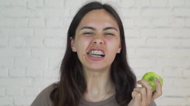 Yeşil elma ve gülümseme yeme dişlerini üzerinde parantez kadın var. Beyaz. Portre