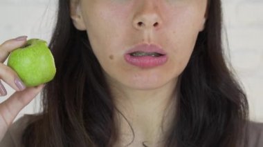 Yeşil elma ve gülümseme yeme dişlerini üzerinde parantez kadın var. Beyaz. Portre