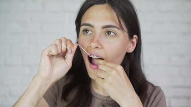 Fio dental. Retrato de rapariga. Limpeza dos dentes, aparelhos dentários . — Vídeo de Stock