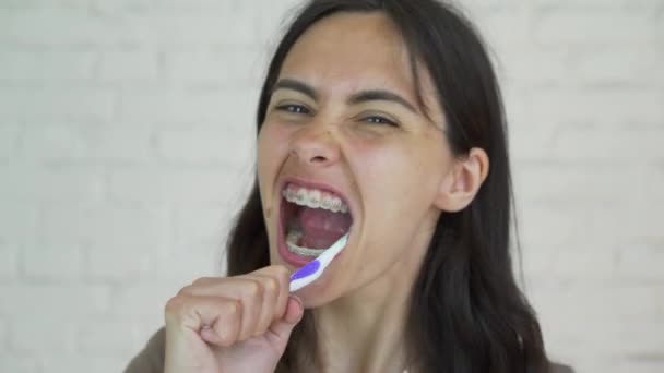 Chica limpieza de dientes con aparatos ortopédicos . — Vídeos de Stock