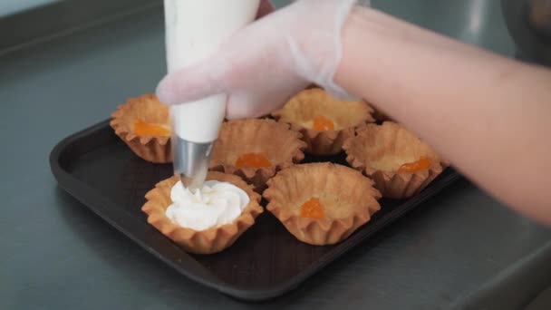 Διακόσμηση Κύπελλο-τούρτα με κρέμα. Χρησιμοποιώντας μαγειρικής σακούλα, ζαχαροπλάστης κάνοντας πολύχρωμα cupcakes για το κόμμα. Στιγμιότυπο από γυναικεία χέρια βάζοντας βούτυρο κρέμα τα νόστιμα κέικ, έννοια σπίτι αρτοποιίας — Αρχείο Βίντεο