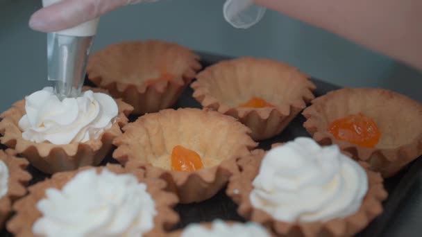 Tasse-Kuchen mit Sahne verzieren. mit Kochtasche, Konditor Herstellung von bunten Cupcakes für Party. Schuss Frauenhände, die Buttercreme auf die leckeren Kuchen legen, Konzept der Hausbäckerei — Stockvideo