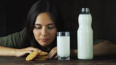 Bir bardak süt yavaş çekimde bir çerez koyarak el. Gıda sinema sahnesi