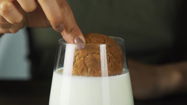 Mão colocando um biscoito em um copo de leite em câmera lenta. Cena cinematográfica de alimentos — Vídeo de Stock