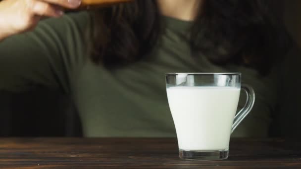 Склянка молока з булочкою на столі . — стокове відео