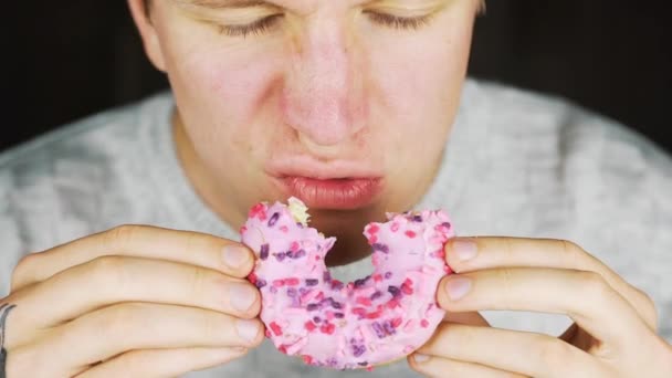 Porträtt av en ung hungrig man äta en munk — Stockvideo