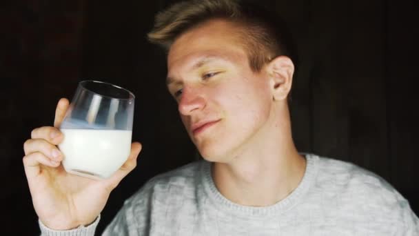 Un uomo che beve bevande proteiche. Un bicchiere di latte nelle mani di un giovane, un SIP di latte fresco — Video Stock