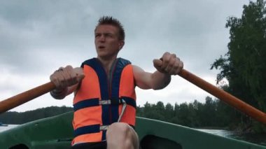 Genç bir adam, bir teknenin su üzerinde ahşap kürek kürek. Bir adama can yeleği.