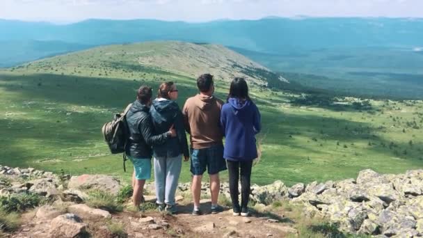 Bir grup arkadaşıyla birlikte, dağın tepesinde oturan turist — Stok video