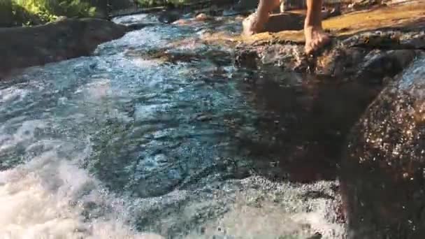 Man swimming in shallow waters of a river in the middle of rocks and stones. — Stock Video