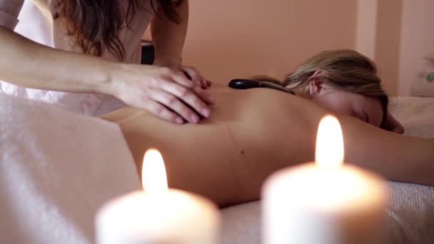 Hermoso cliente étnico siendo tratado con terapia de piedra caliente en un spa de lujo — Vídeo de stock