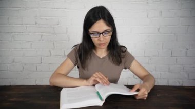 Bir kitap okuma gözlükleri ile beyaz bir masada oturan kız günlüğü. Kötü görme.