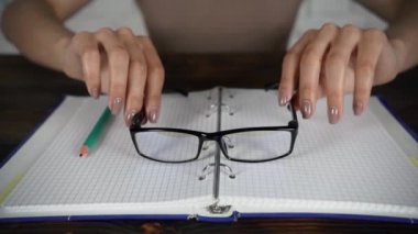 Bir kitap okuma gözlükleri ile beyaz bir masada oturan kız günlüğü. Kötü görme.