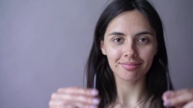 Genç kadın yeni gözlüklerini gri arka planı yansıtmadaki içinde kontrol. Gri arka plan üzerinde gözlüklü genç kadın. Gözlük ile güzel kız.