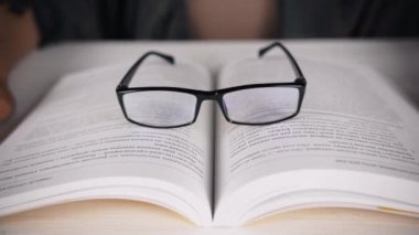Bir kitap okuma gözlükleri ile beyaz bir masada oturan kız günlüğü. Kötü görme.