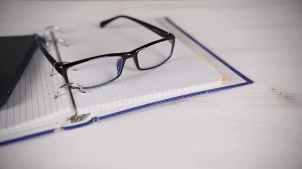 Bir kitap okuma gözlükleri ile beyaz bir masada oturan kız günlüğü. Kötü görme. — Stok video
