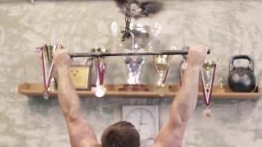 Gömleksiz sporcu spor salonunda çapraz eğitim egzersiz sırasında Pull-up çubuklarında yapıyor, yukarı eğimli