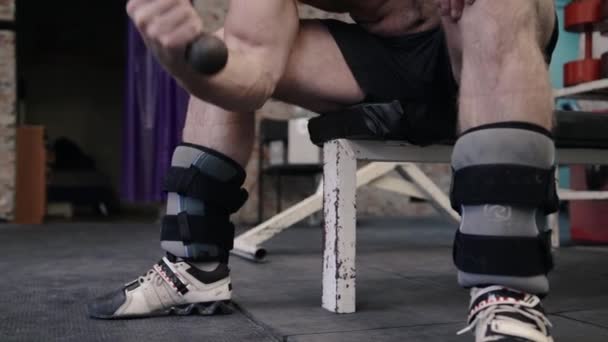 Guy fléchissant les bras avec des haltères dans ses mains, séance d'entraînement de gymnastique, gros plan sur le corps — Video