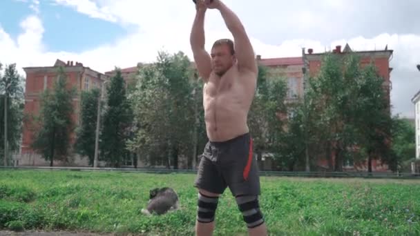 Un uomo forte, crossfit, che prende i kettlebell con entrambe le mani e li lancia al rallentatore — Video Stock