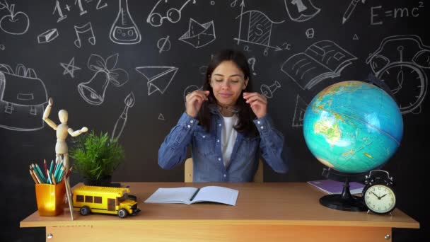 Portrait of a beautiful schoolgirl student , thinking about choosing a profession, on the background of a black Board with a globe . Concept: ideas, school, University, education. — Stock Video