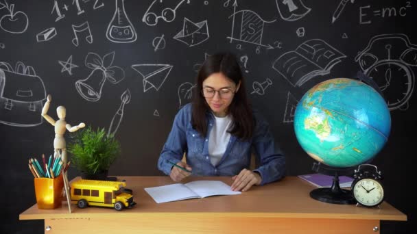 Retrato de uma bela estudante, pensando em escolher uma profissão, no fundo de uma placa preta com um globo. Conceito: ideias, escola, Universidade, educação . — Vídeo de Stock