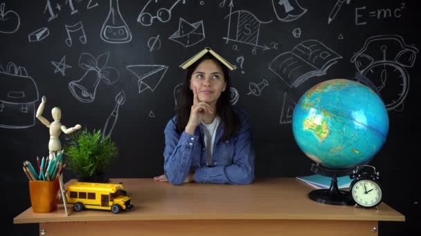 Retrato de uma bela estudante, pensando em escolher uma profissão, no fundo de uma placa preta com um globo. Conceito: ideias, escola, Universidade, educação . — Vídeo de Stock