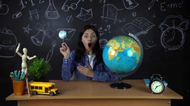 Porträt einer schönen Schülerin, die über die Berufswahl nachdenkt, vor dem Hintergrund einer schwarzen Tafel mit einer Weltkugel. Konzept: Ideen, Schule, Universität, Bildung. — Stockvideo