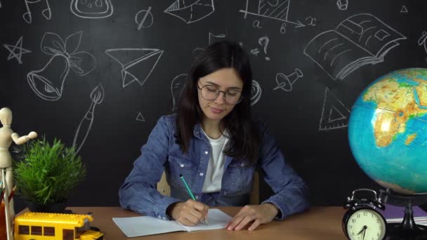 Μαθητρια, φοιτητρια που κάθεται σε ένα γραφείο, κάνει την εργασία. Εκπαίδευση στο σχολείο, κολέγιο, Πανεπιστήμιο — Αρχείο Βίντεο