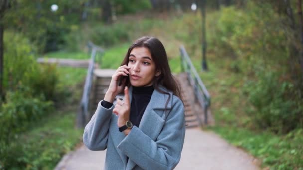 Mujer hablando en un teléfono móvil en el parque de cerca — Vídeos de Stock