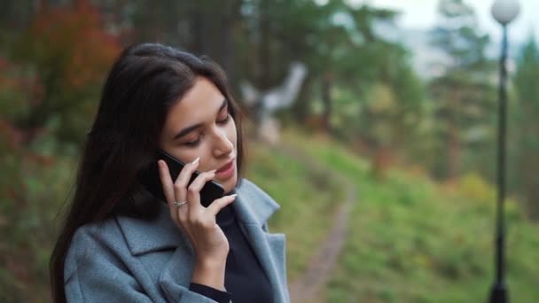 Женщина разговаривает по мобильному телефону в парке крупным планом — стоковое видео