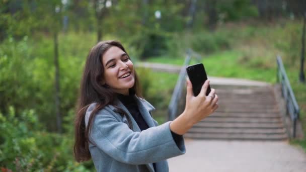 Šťastná mladá žena, posílání sms, SMS v parku — Stock video