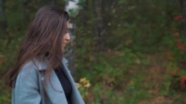 güzel genç esmer kız sonbaharda parkta yürüyüş.