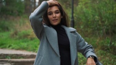 güzel genç esmer kız sonbaharda parkta yürüyüş.