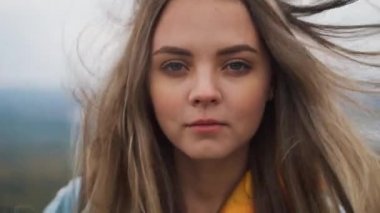 Güzel kadın kamera ayakta dağın zirvesinde bakarak.