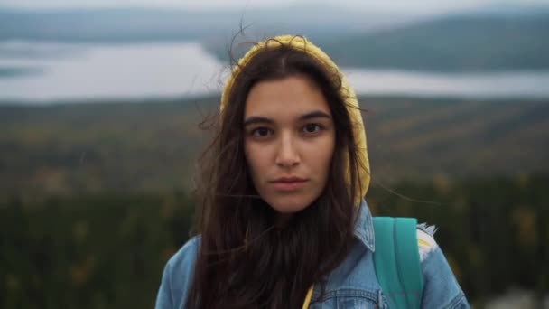 Mulher bonita olhando para a câmera em pé no topo da montanha . — Vídeo de Stock